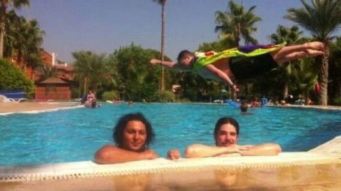 Hilarious photo of a man mid-air over a pool while two people look on, moments before disaster struck.