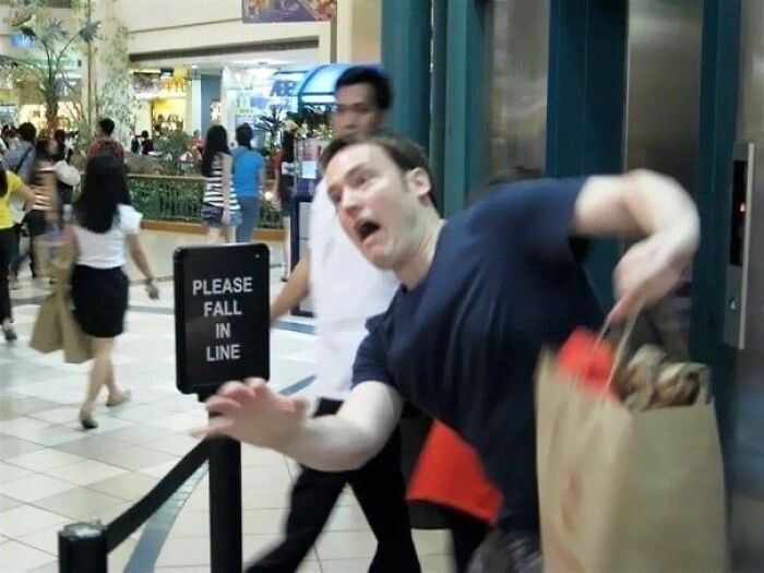 Hilarious photo of a man tripping with shopping bags next to an elevator, moments before disaster struck.