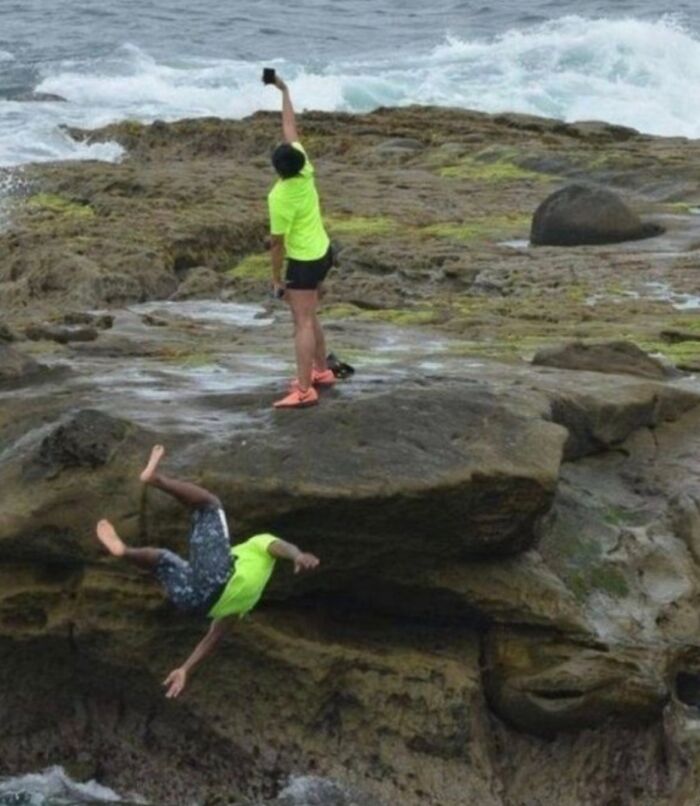 A hilarious photo taken moments before disaster struck: a man falling off a cliff as another takes a selfie.