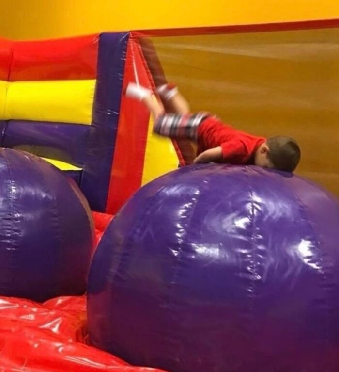 A young boy tumbles headfirst onto a purple inflatable, captured moments before disaster struck.