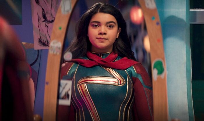 A young woman in a superhero movie costume with a red scarf and gold emblem, reflecting in a mirror, as Gen Z superhero movies character. A young woman in a superhero movie costume with a red scarf and gold emblem, reflecting in a mirror, as Gen Z superhero movies character.