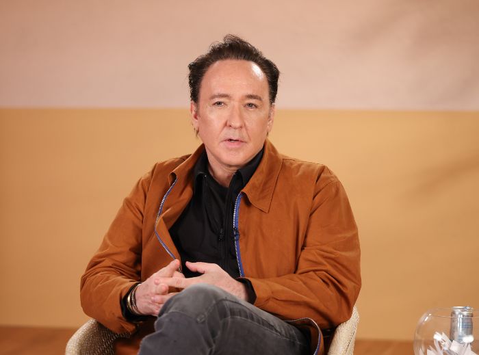 John Cusack vanished from Hollywood, pictured in a brown jacket, discussing his absence and sister Joan's return.