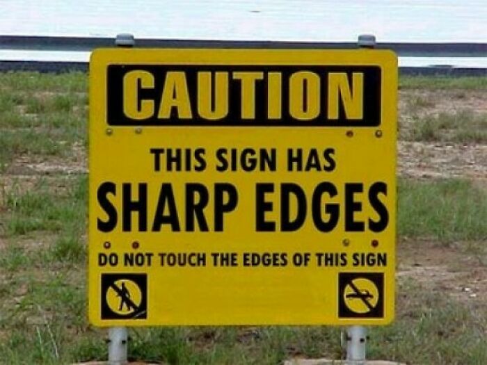 Hilariously dumb warning label: A bright yellow sign reads, CAUTION THIS SIGN HAS SHARP EDGES. Do not touch.