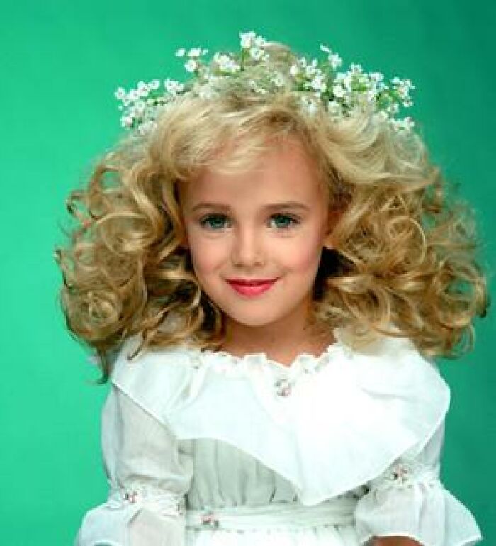 A young JonBenet Ramsey in a white dress with flowers, a notorious unsolved mystery.