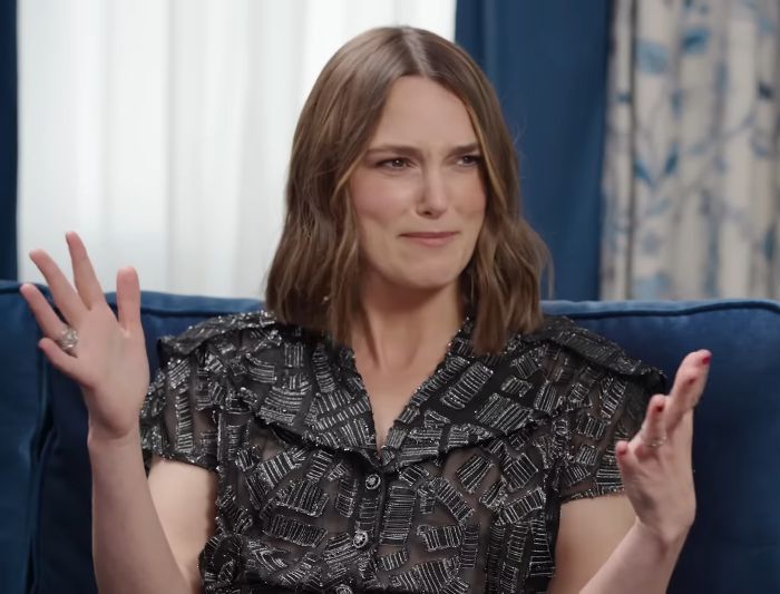 Keira Knightley expressing confusion with raised hands during an interview.