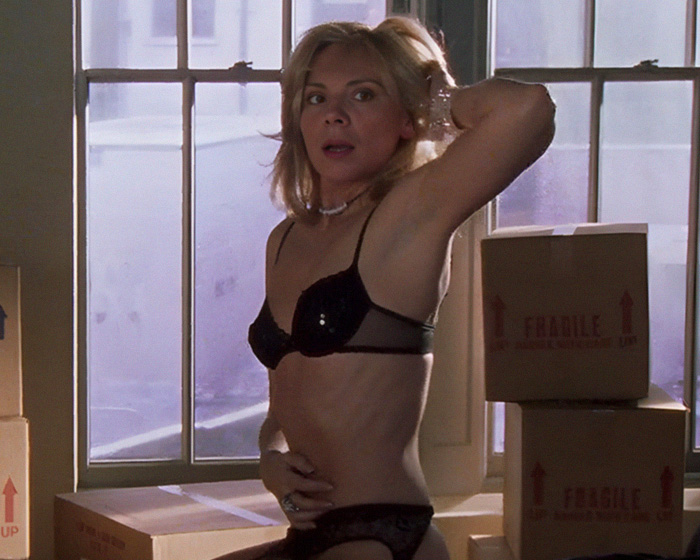 Woman in black lingerie posing in a scene with moving boxes behind the scenes