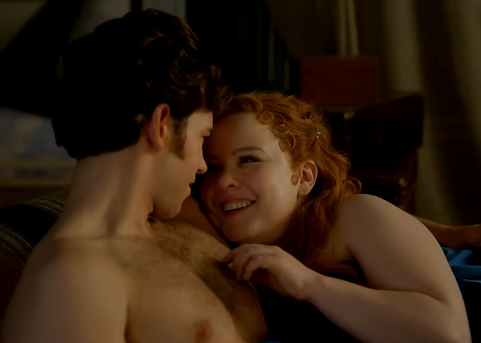 Intimate scene showing a couple sharing a tender moment in bed behind the scenes
