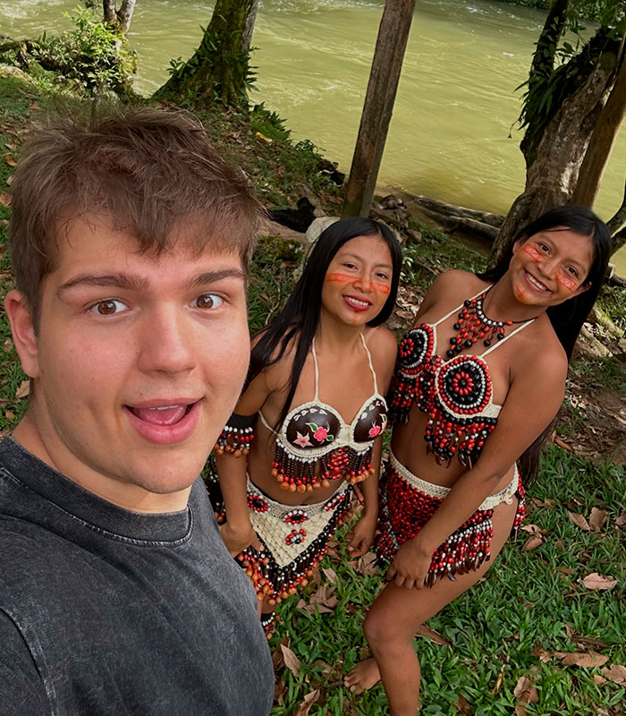 A man taking a selfie with two Amazonian women from a remote tribe by a river, highlighting his immersion. A man taking a selfie with two Amazonian women from a remote tribe by a river, highlighting his immersion.