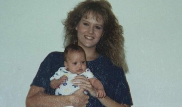 A smiling woman with curly hair holding a baby, an image that could be connected to mysteries and who is to blame.