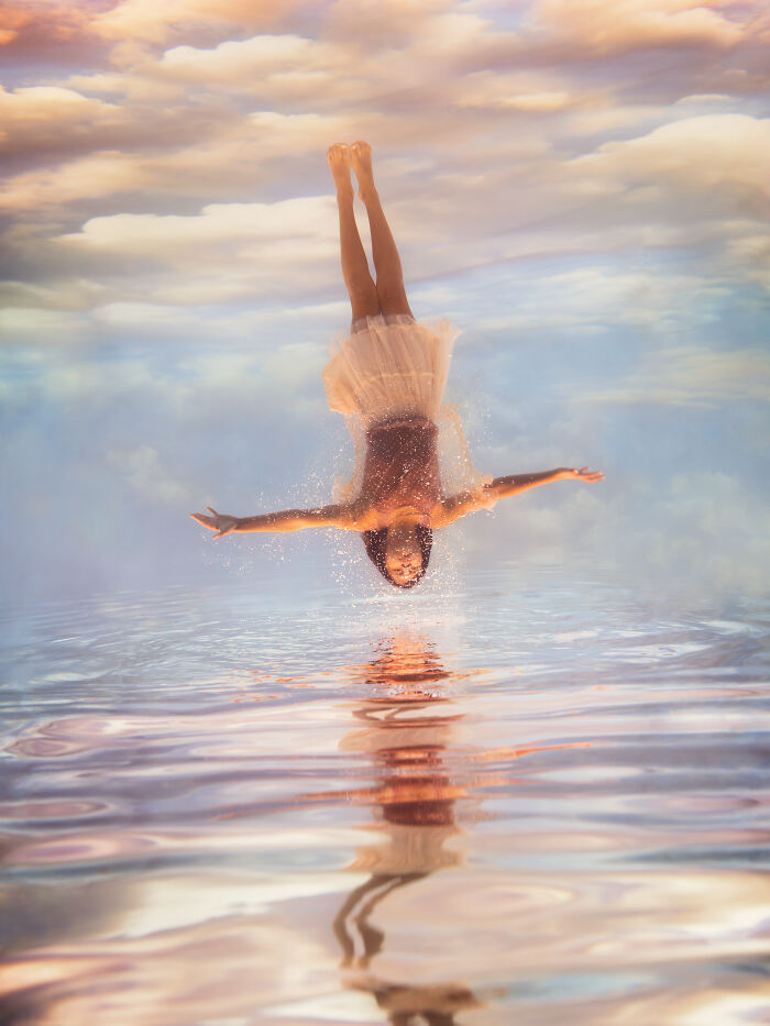 A woman is captured mid-air, diving into water, creating surreal photos with splashes, set against a cloudy sky.