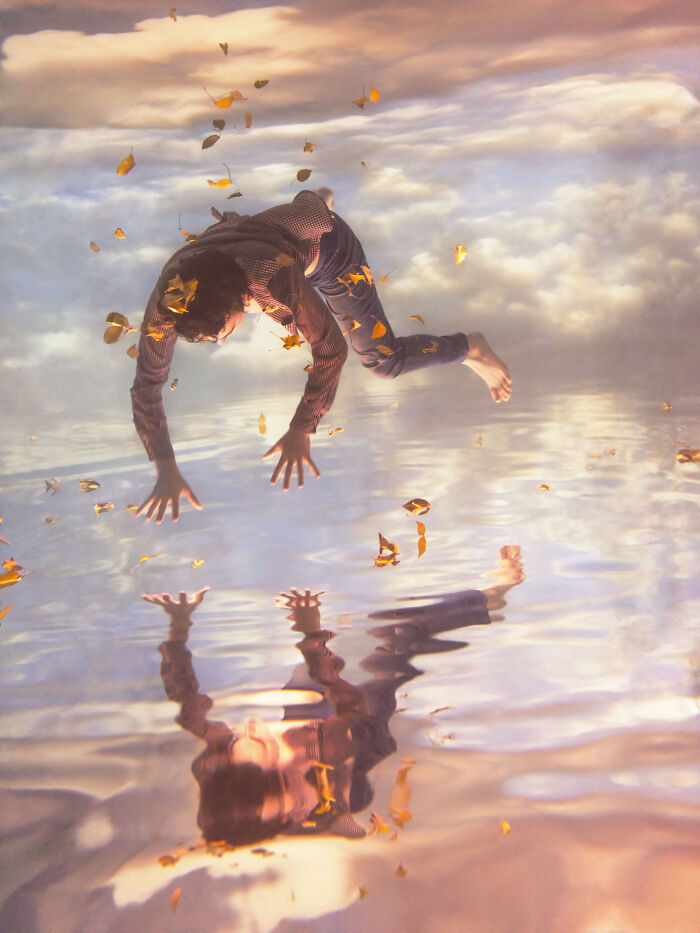 A woman creates surreal photos by submerging herself in water, with autumn leaves falling around her reflection.