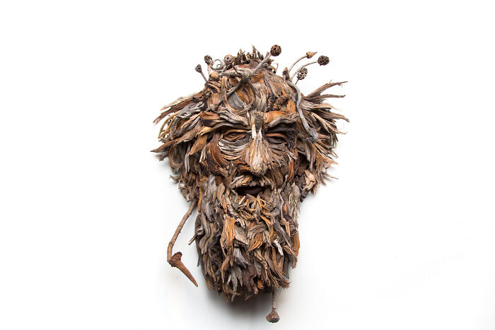 Detailed wood sculpture of a bearded face with natural elements, created from collected wood pieces.