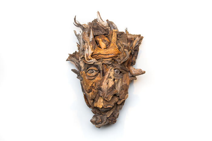 Intricate wood sculpture of a face with expressive eyes, crafted from diverse pieces of wood.