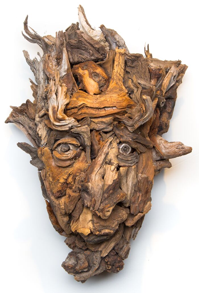 Intricate wood sculpture of a face with expressive eyes, crafted from diverse pieces of wood.