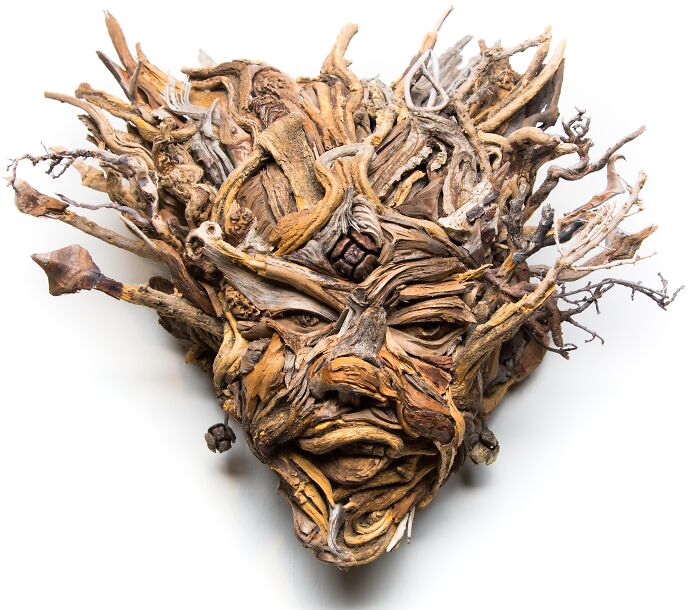 Captivating wood sculpture of a face with flowing hair-like elements, artfully constructed from collected wood pieces.