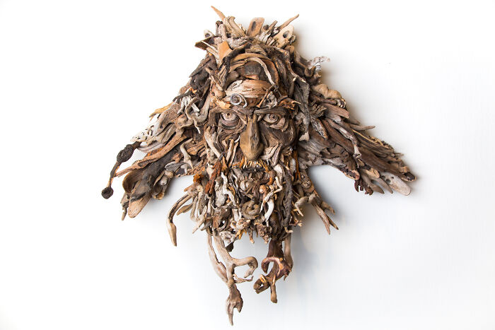Intricate wood sculpture of a face with a wild, natural beard, crafted from collected pieces of wood.