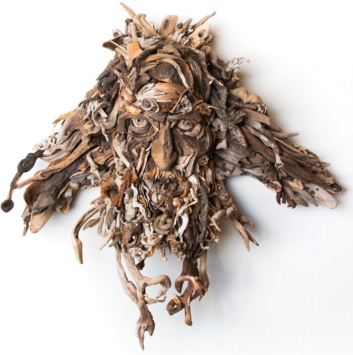 Intricate wood sculpture of a face with a wild, natural beard, crafted from collected pieces of wood.