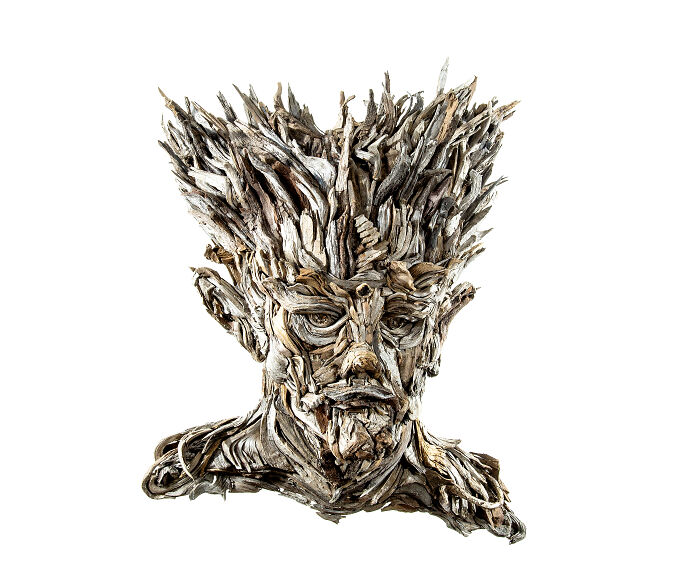 A stunning sculpture of a regal head with spiky hair, entirely composed of collected pieces of wood.