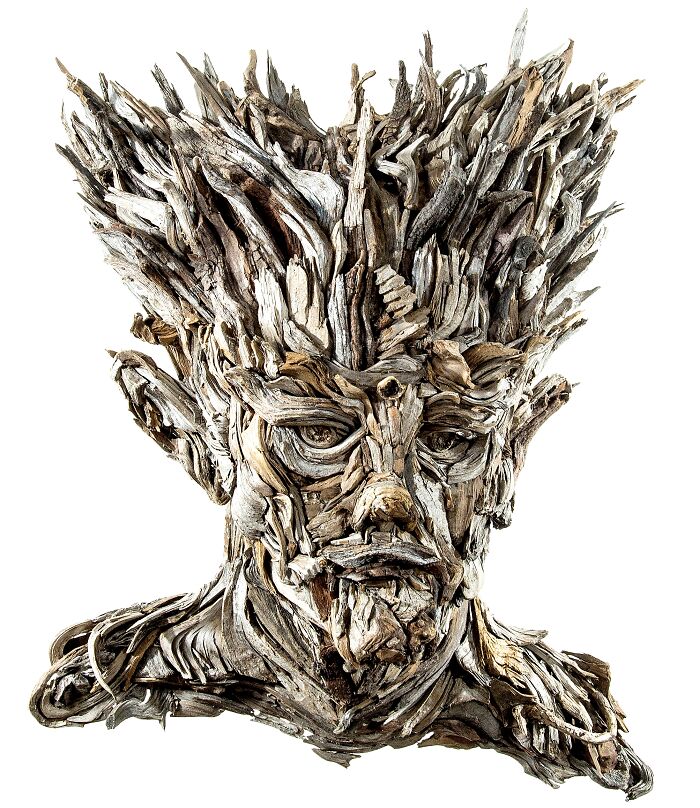 A stunning sculpture of a regal head with spiky hair, entirely composed of collected pieces of wood.