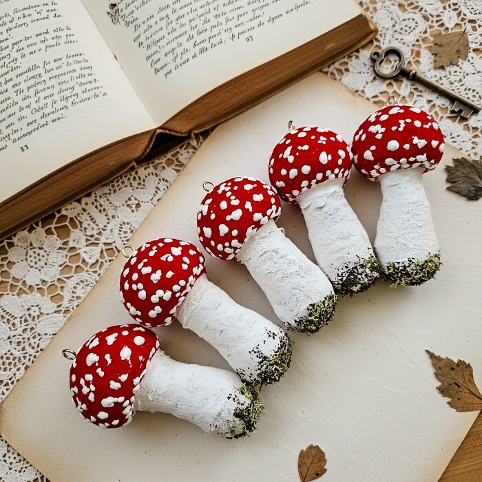 Handmade cotton wool creations of five red and white spotted mushrooms, by an artist who creates art.
