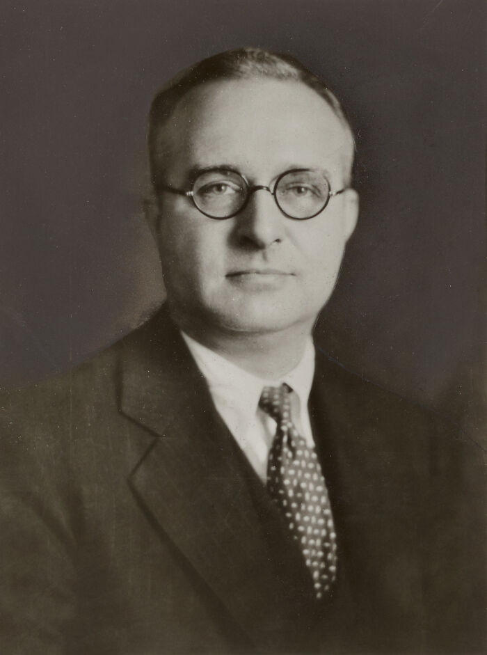 A sepia-toned portrait of a man in glasses and a suit, among disturbing facts.
