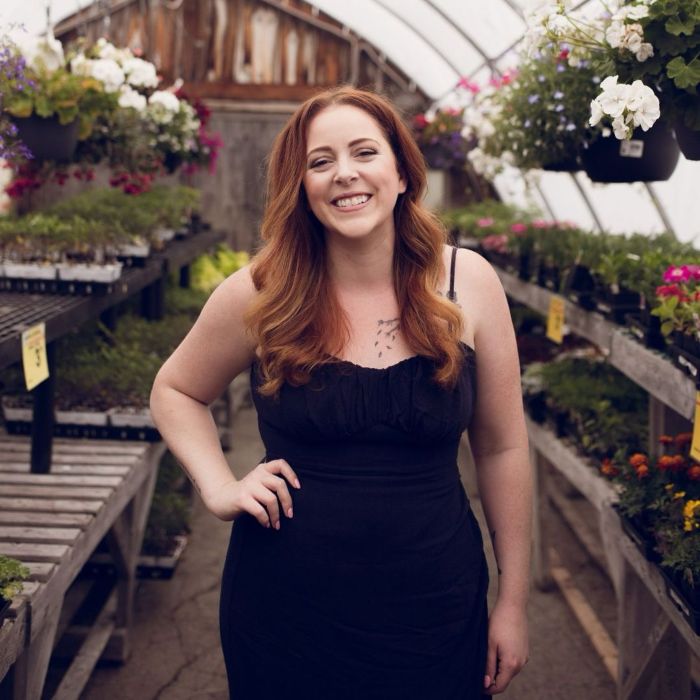 Smiling adult content creator standing in a greenhouse with plants, revealing frustrating attitude of married men. Smiling adult content creator standing in a greenhouse with plants, revealing frustrating attitude of married men.