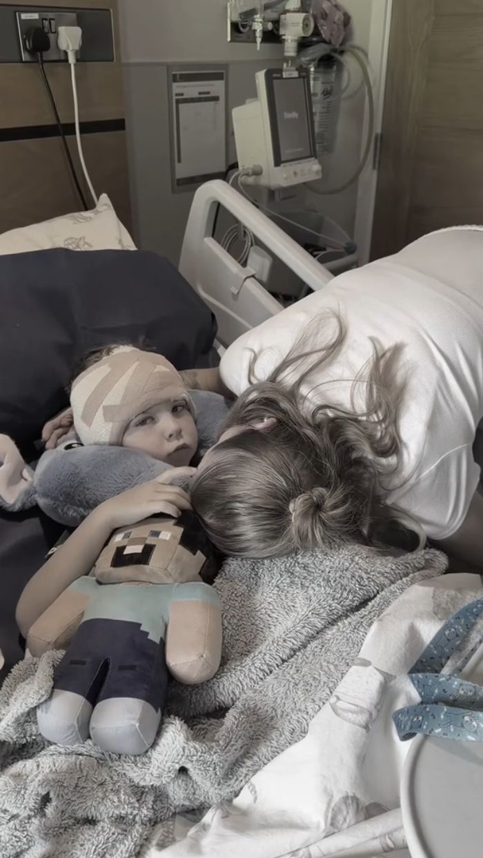 A mom comforts her 5YO boy in a hospital bed after cosmetic surgery, a controversial choice. A mom comforts her 5YO boy in a hospital bed after cosmetic surgery, a controversial choice.