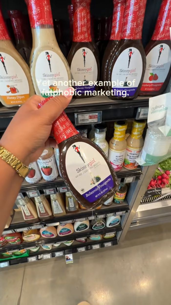 A hand holding a bottle of Skinnygirl brand balsamic vinaigrette, criticizing fatphobic marketing. A hand holding a bottle of Skinnygirl brand balsamic vinaigrette, criticizing fatphobic marketing.