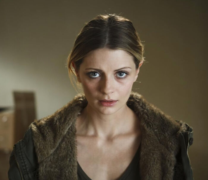 A woman with light brown hair and blue eyes, looking at the camera, conveying disillusionment by celebrities.