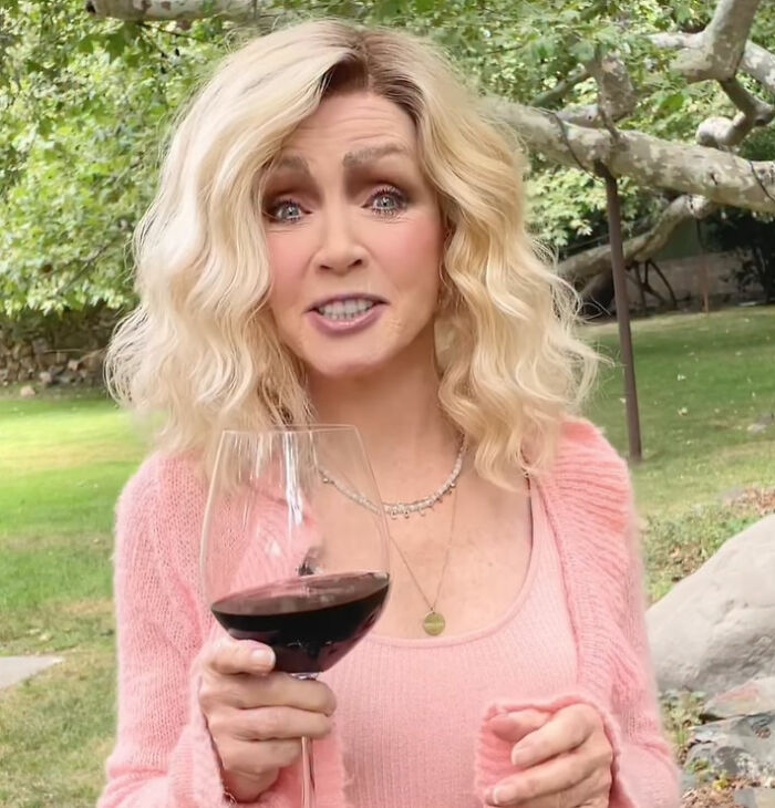 A Hollywood star holding a glass of red wine, looking surprised, discussing her reasons for joining an adult content platform at 85. A Hollywood star holding a glass of red wine, looking surprised, discussing her reasons for joining an adult content platform at 85.