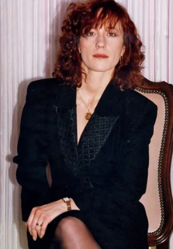 A woman with curly red hair, sitting, a person involved in a famous mystery case.