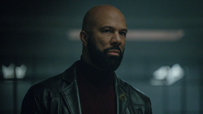 A bald man with a beard, a returning character in the Silo Season 3 cast, wearing a leather jacket. A bald man with a beard, a returning character in the Silo Season 3 cast, wearing a leather jacket.