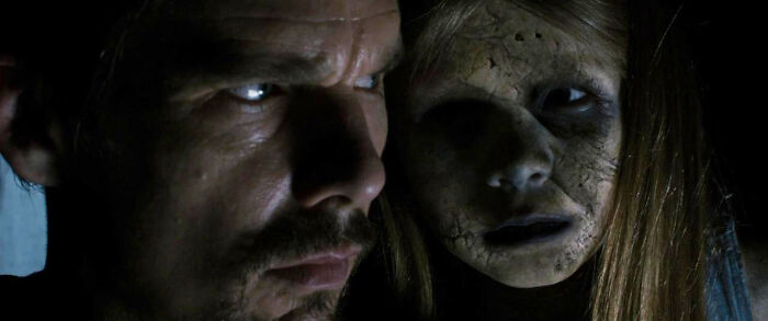 A man with a worried expression next to a ghostly, pale girl, from a terrifying horror movie.