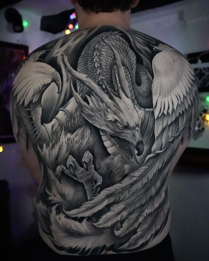 Black and grey dragon tattoo art covering a man's entire back, an inspiring example of tattoo art.