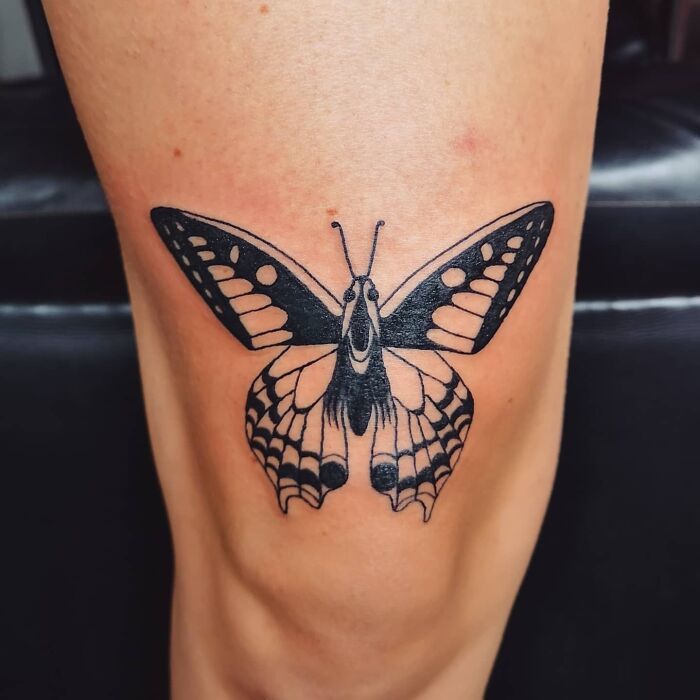 Detailed black and white butterfly tattoo art on a person's leg, a beautiful example of tattoo art.