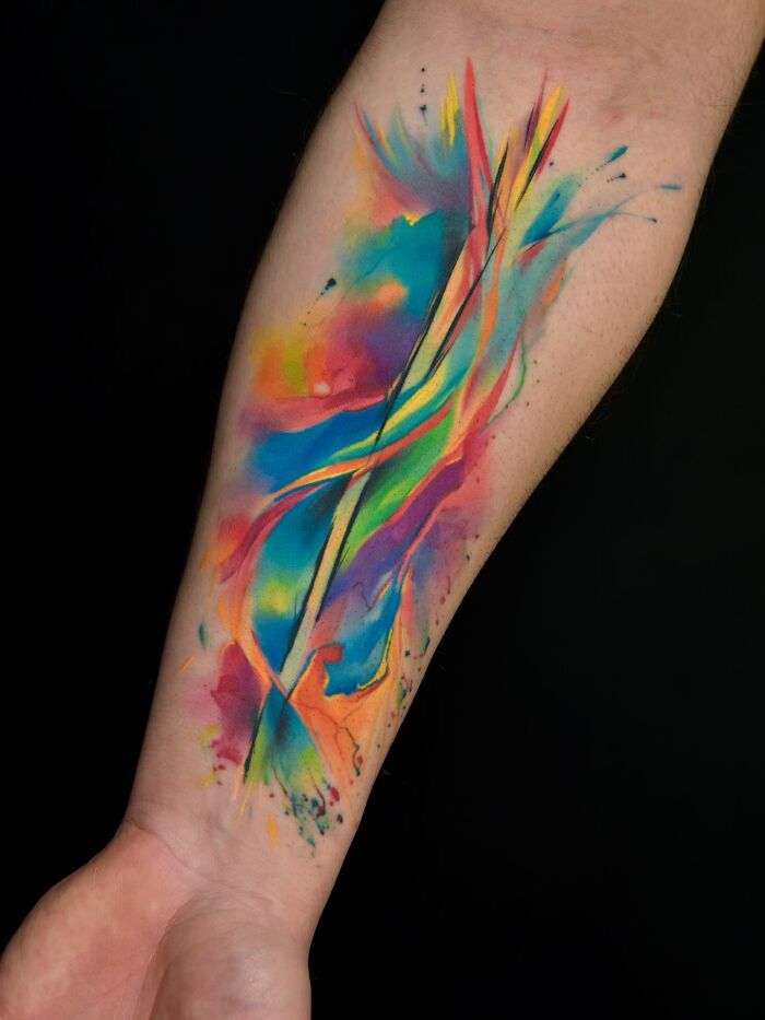 Colorful watercolor style tattoo art on a forearm, an inspiring example of modern tattoo art.