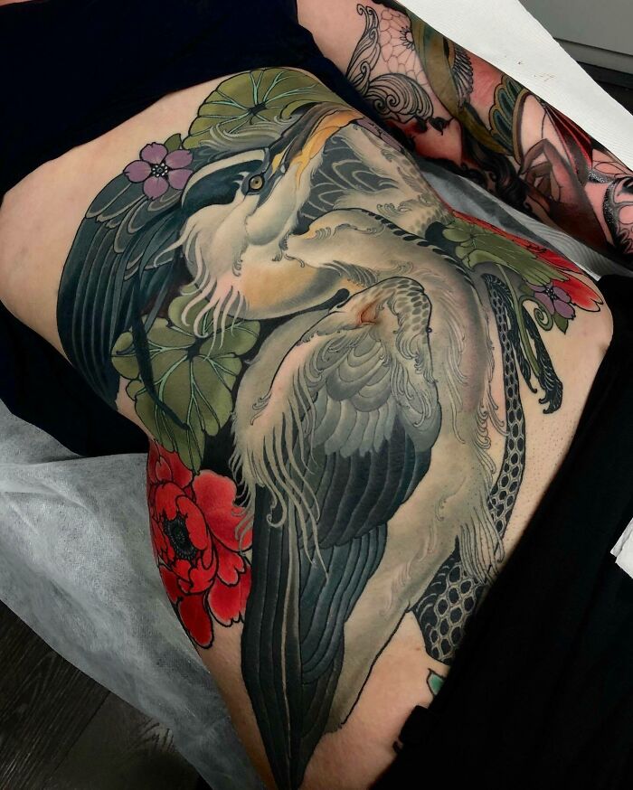 Large, detailed tattoo art of cranes and flowers covering a thigh, showcasing inspiring examples of tattoo art.