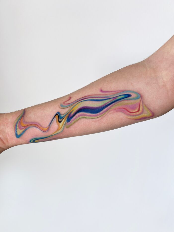 Vibrant abstract tattoo art swirling in multiple colors on an arm, an inspiring example of tattoo art.