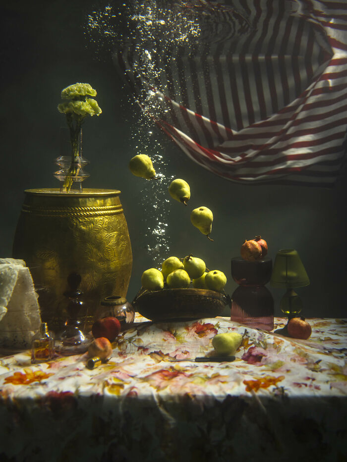 Surreal photos of pears and flowers submerged in water, surrounded by bubbles and a floating striped cloth.