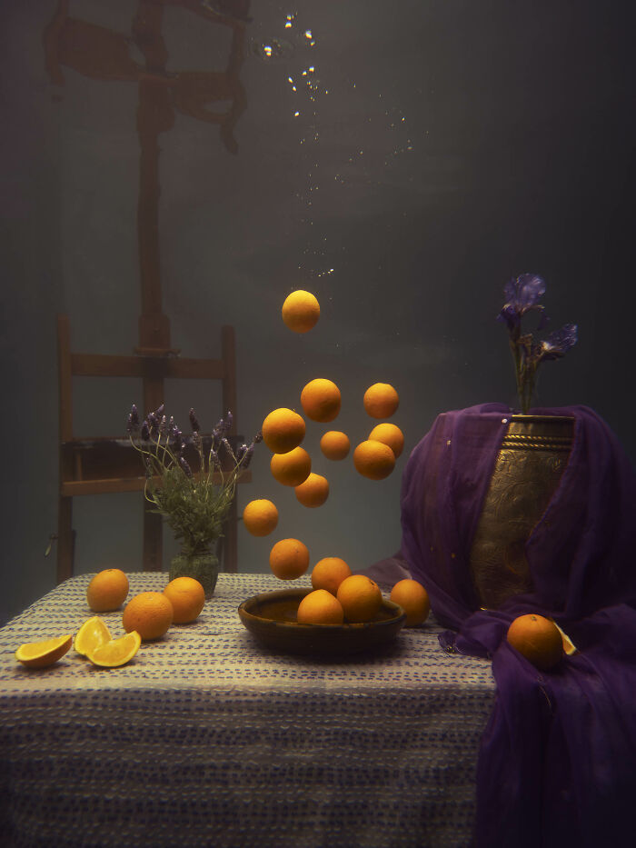 Surreal photos of oranges floating in water, submerged in an artistic still life composition.