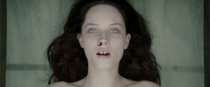 A pale woman with white eyes and a bloody nose, a terrifying image from horror movies.