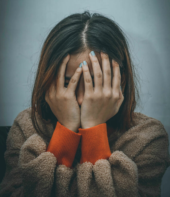 A woman with her face in her hands, revealing subtle signs someone isn't as nice as they pretend to be.