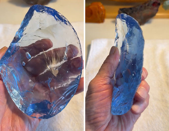 A hand holding a clear, blue-tinted, irregularly shaped glass object, part of a mysterious Mojave Desert discovery. A hand holding a clear, blue-tinted, irregularly shaped glass object, part of a mysterious Mojave Desert discovery.