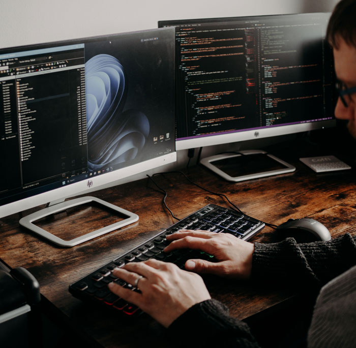 A dedicated IT Guy works on two computer monitors, highlighting the impact on IT Guy. A dedicated IT Guy works on two computer monitors, highlighting the impact on IT Guy.