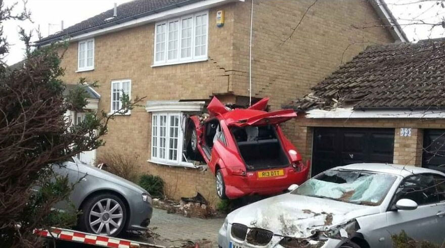 A red car had a rough day behind the wheel, crashing into the side of a brick house.