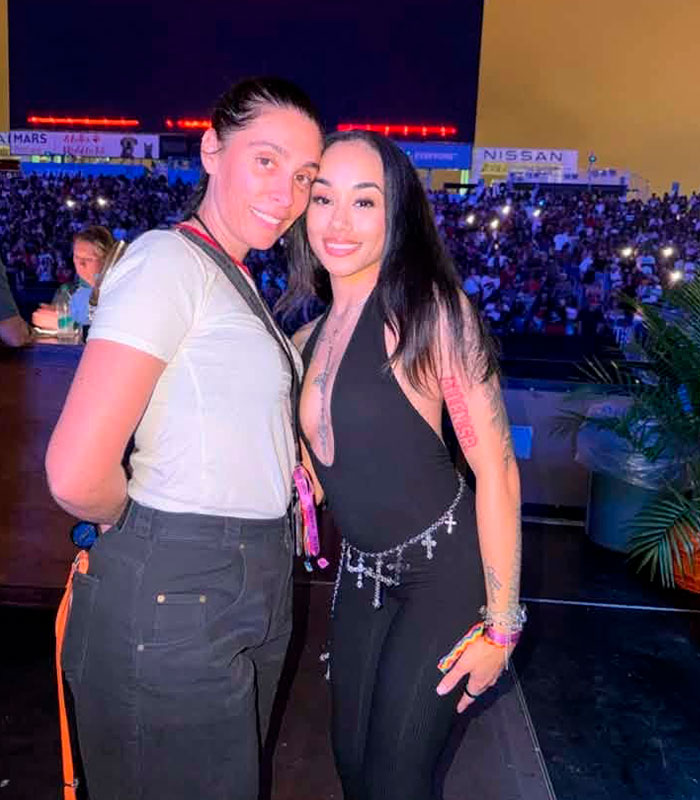 Woman in black jumpsuit, who had an awkward reaction to Usher's seductive moves, posing with another woman.