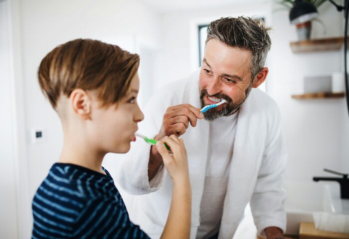 A father and son brushing their teeth together, a heartwarming scene within someone's home.