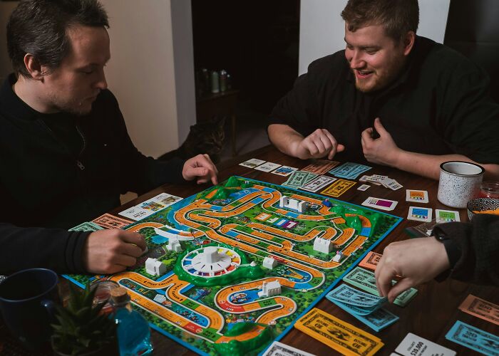 Friends gathered around a table playing a board game, creating a welcoming atmosphere in someone's home.