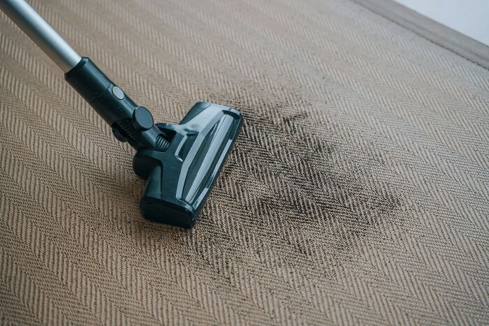 A vacuum cleaner cleaning a dirty rug, reflecting a messy home where guests might not want to return.