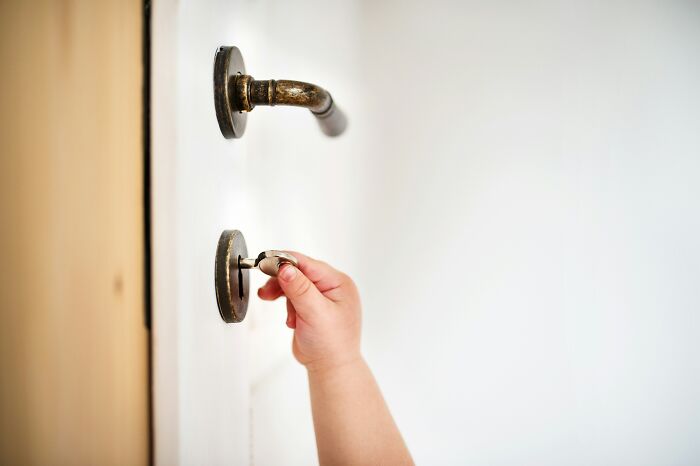 A child's hand inserting a key into a lock, representing guests entering or securing someone's home.